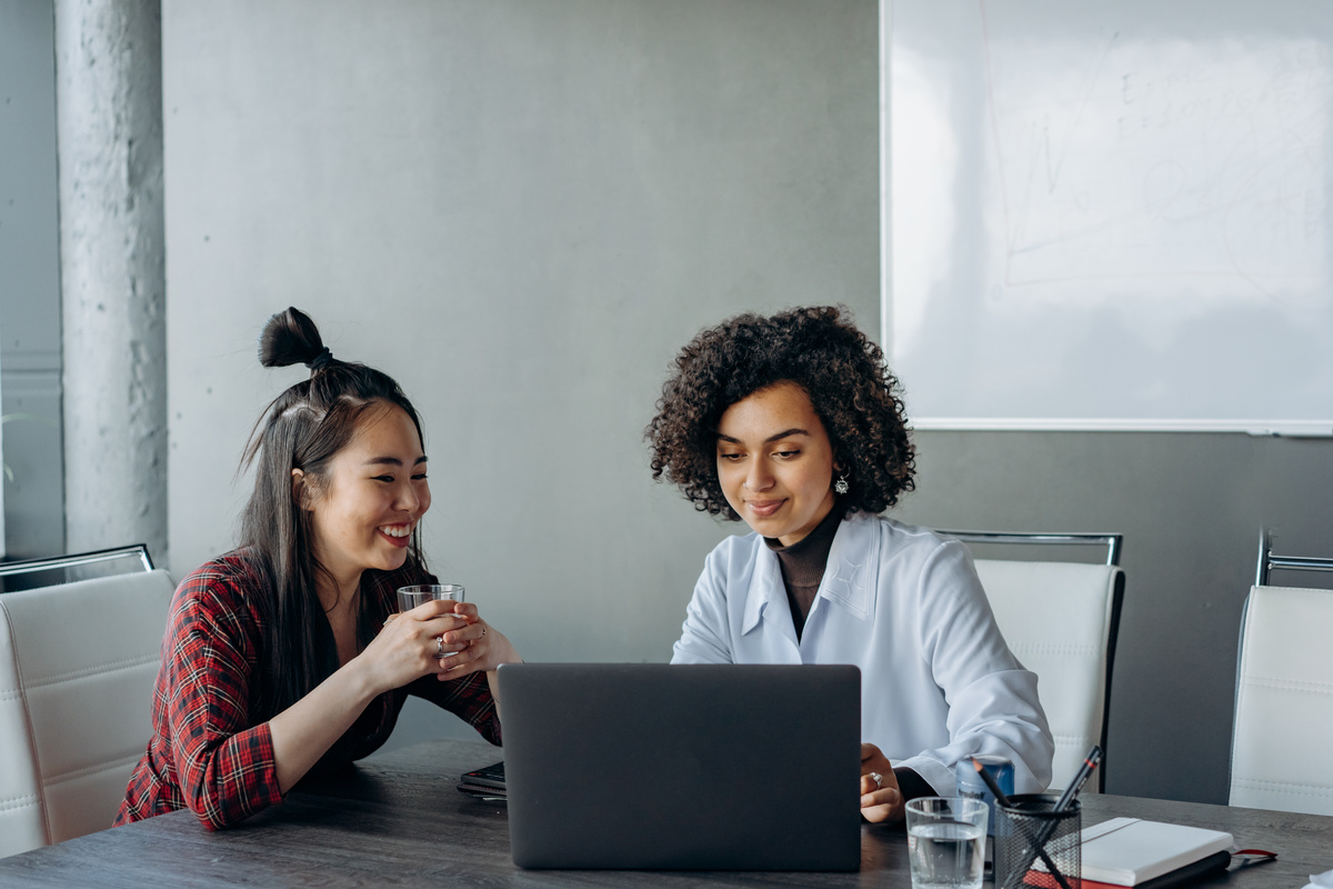 Women Having a Conversation while Looking at the Screen of a Laptop